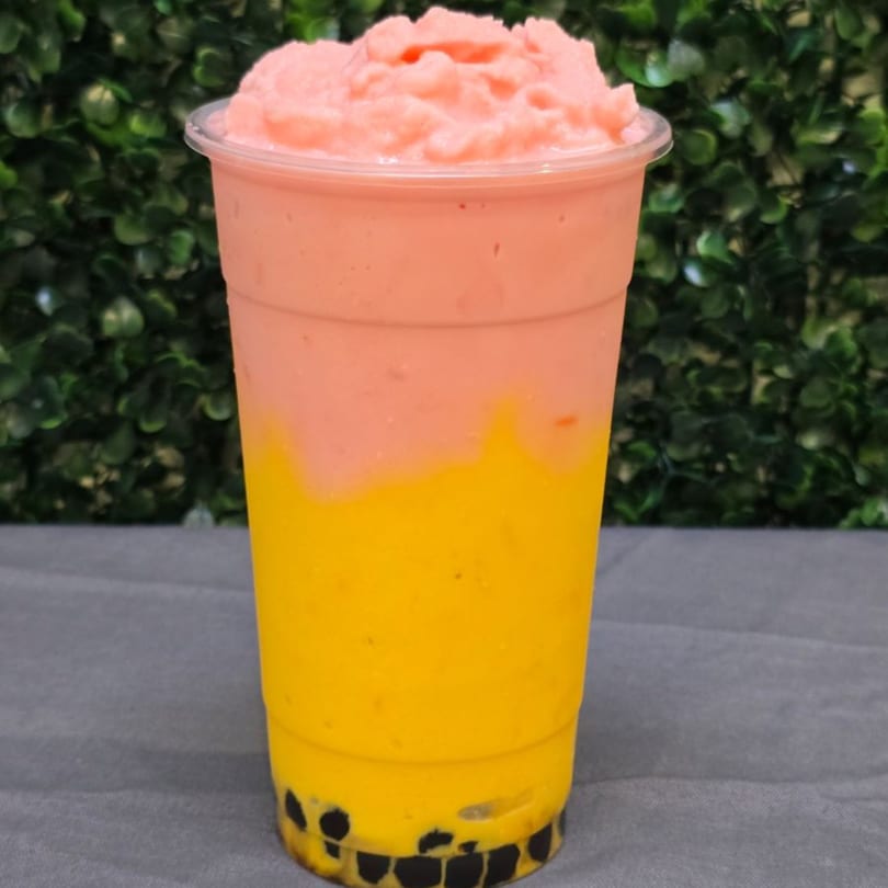 A vibrant two-toned drink with pink slush on top, yellow liquid in the middle, and boba pearls at the bottom.