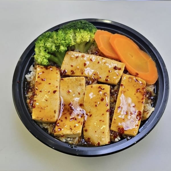 Tofu poke bowl with broccoli and carrots, topped with a spicy sauce.